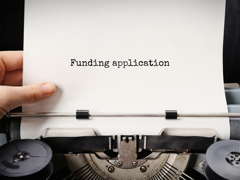 A typewriter with piece of paper with the words Funding Application